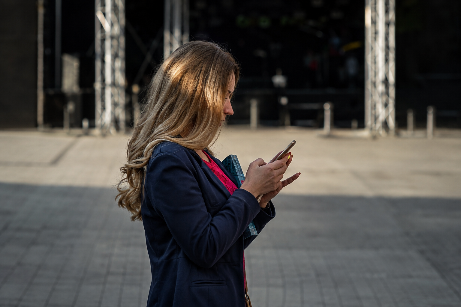 Woman in a blue blazer using her smartphone outdoors.
